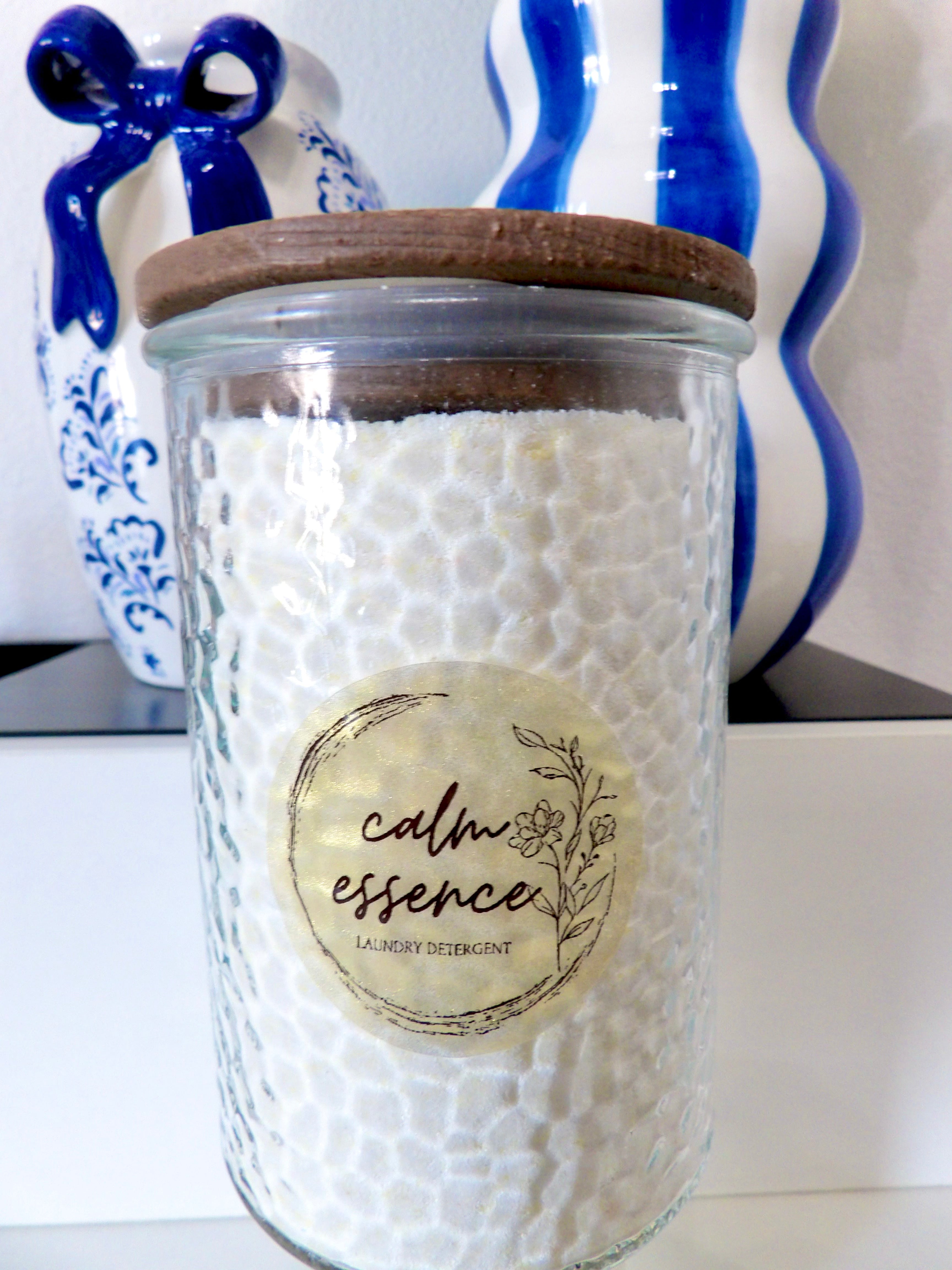 Jar of laundry detergent labeled 'calm essence' with decorative background